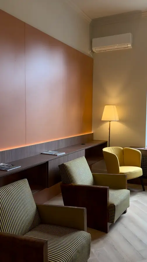 Filmare pe telefon din sala de așteptare: peretele ocru cu banda de lumină, fotoliile Art Deco, fereastra înaltă spre grădină, apoi ușile albe duble care dau în cabinet.